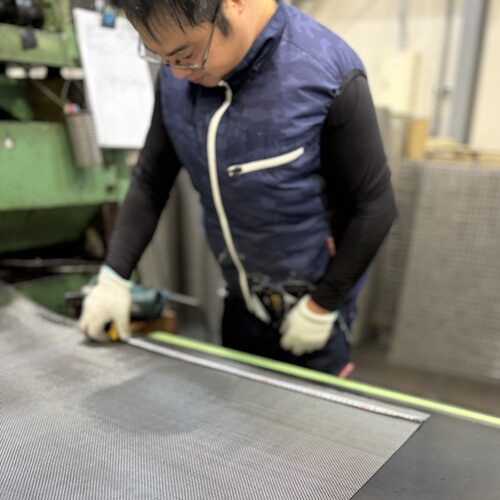 平織金網を切断する前にスケールで寸法を測定している様子