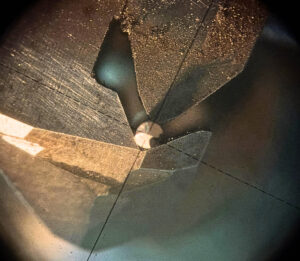 パンチングメタル用ドリルの刃先を研磨盤越しに超拡大した様子。芯出し調整の瞬間。