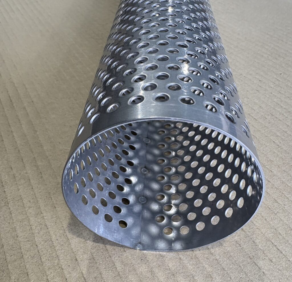 円筒状に巻かれたステンレス製パンチングメタルの筒の断面。穴のパターンや、溶接または突き合わせによる合わせ目が見える。