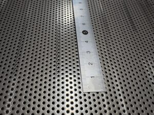 SUS304のパンチングメタルに定規を当て、φ1.5mmの穴径と穴ピッチを示すクローズアップ。