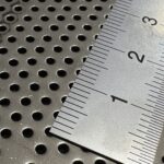 SUS304のパンチングメタルに定規を当て、φ1.5mmの穴径と穴ピッチを示すクローズアップ。