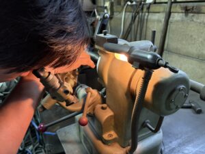 パンチングメタル用ドリルを研磨機で手作業研磨する職人の作業風景。