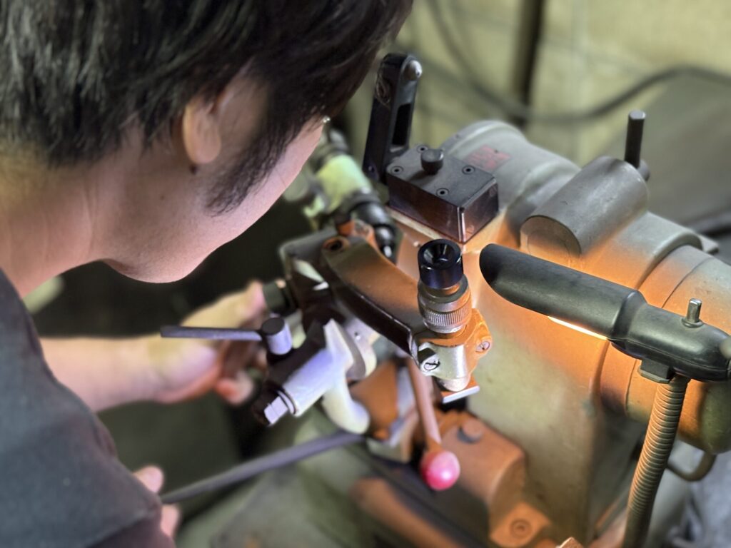 パンチングメタル用ドリルを研磨機で手作業研磨する職人の作業風景。